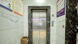 An elevator in a hallway with marble walls, a wooden box, and a sign on the wall. - Harmony One Hotel (Enshi City)