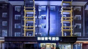 A hotel with a modern facade, featuring a prominent entrance with a glass door and a visible interior with seating and a counter. - Harmony One Hotel (Enshi City)