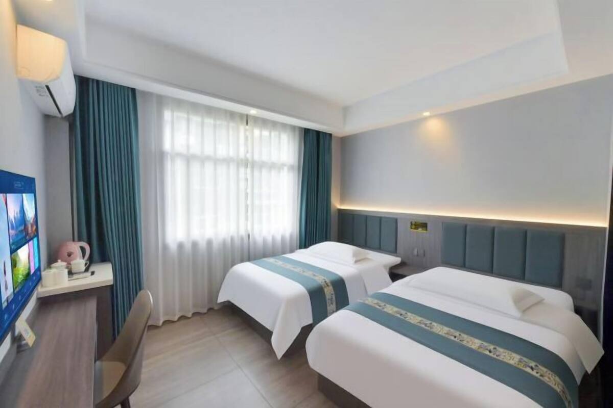 Ein Hotelzimmer mit zwei Betten, einem Schreibtisch mit Computer und einem Fernseher.