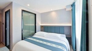 A modern hotel room with a bed, a window with curtains, a headboard, and a wall-mounted light fixture. - Harmony One Hotel (Enshi City)