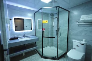 Un baño moderno con ducha de vidrio, lavamanos con espejo e inodoro.