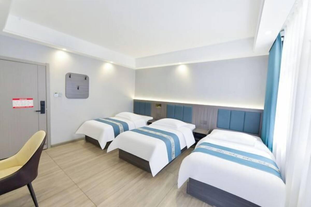 Ein Hotelzimmer mit zwei Betten, einem Schreibtisch, einem Stuhl und einer wandmontierten Bedienkonsole.