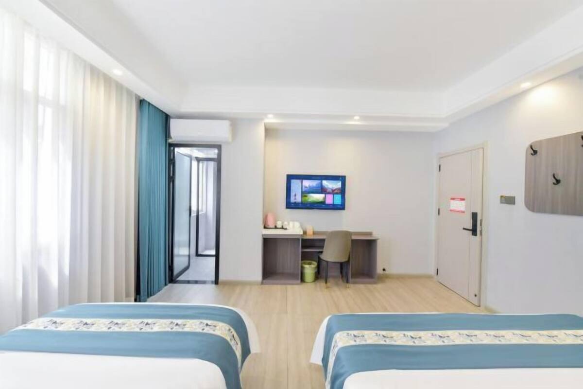 Ein Hotelzimmer mit zwei Betten, einem Schreibtisch mit Stuhl, einem Fernseher und einer Tür.