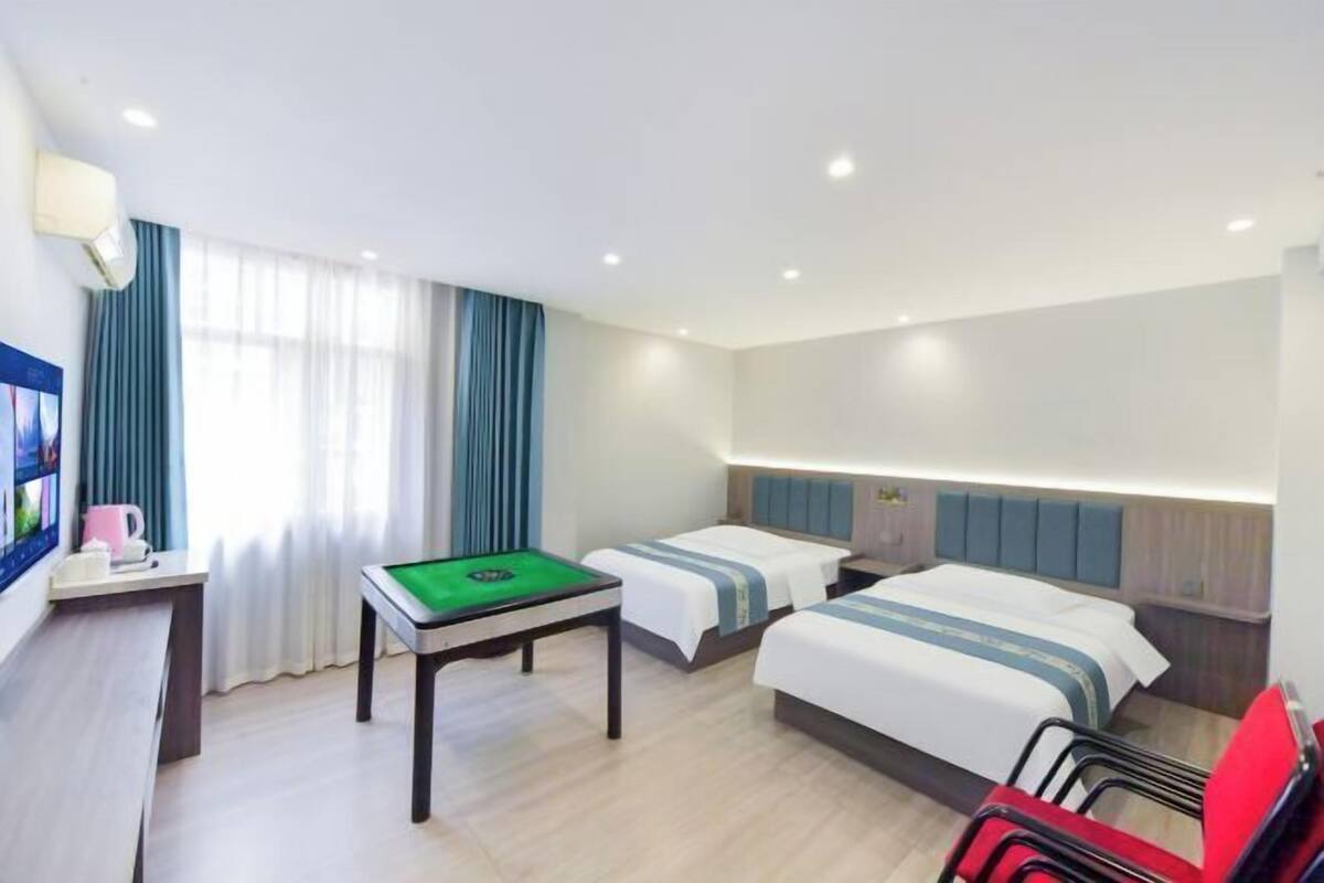 Ein Hotelzimmer mit zwei Betten, einem Billardtisch, einem Schreibtisch mit Lampe und einem Fernseher.