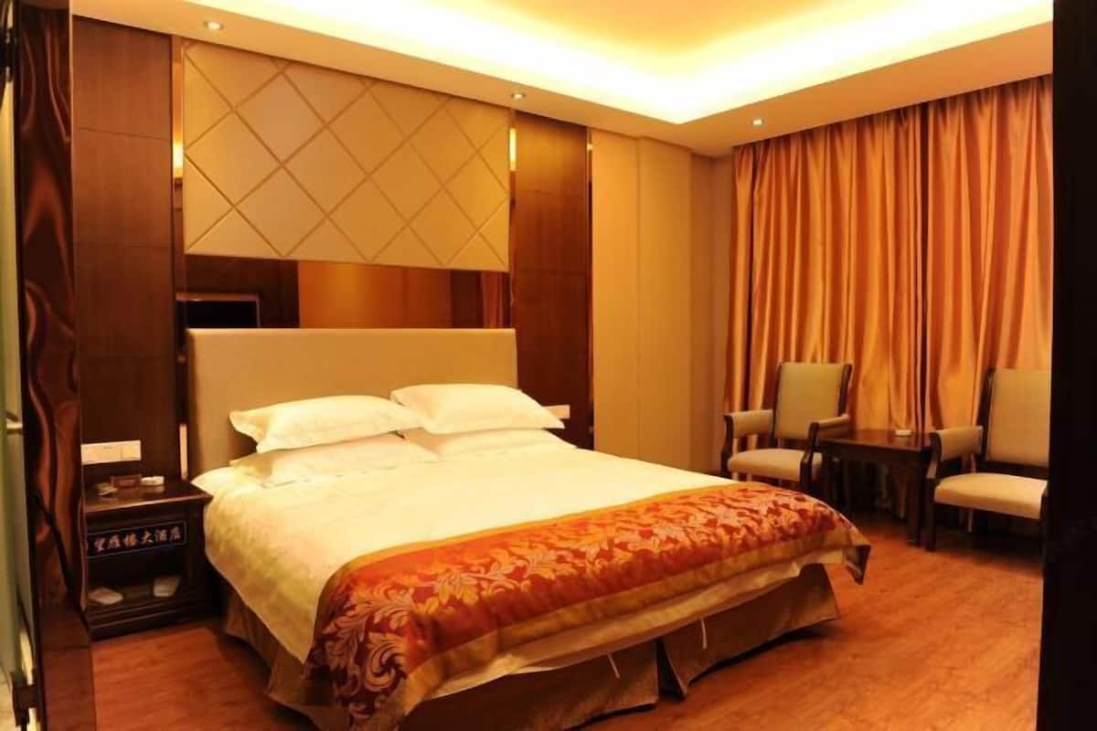 Une chambre d’hôtel avec un grand lit, une table de chevet, une chaise et un bureau.