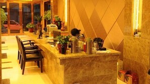 A hotel lobby with a marble reception desk, several chairs, potted plants, and a geometric patterned wall. - Wangyanlou Hotel (Yueqing)