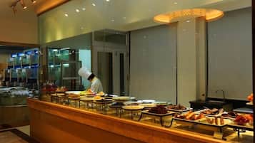A buffet setup with a chef preparing food, a variety of dishes displayed, and a modern interior design.