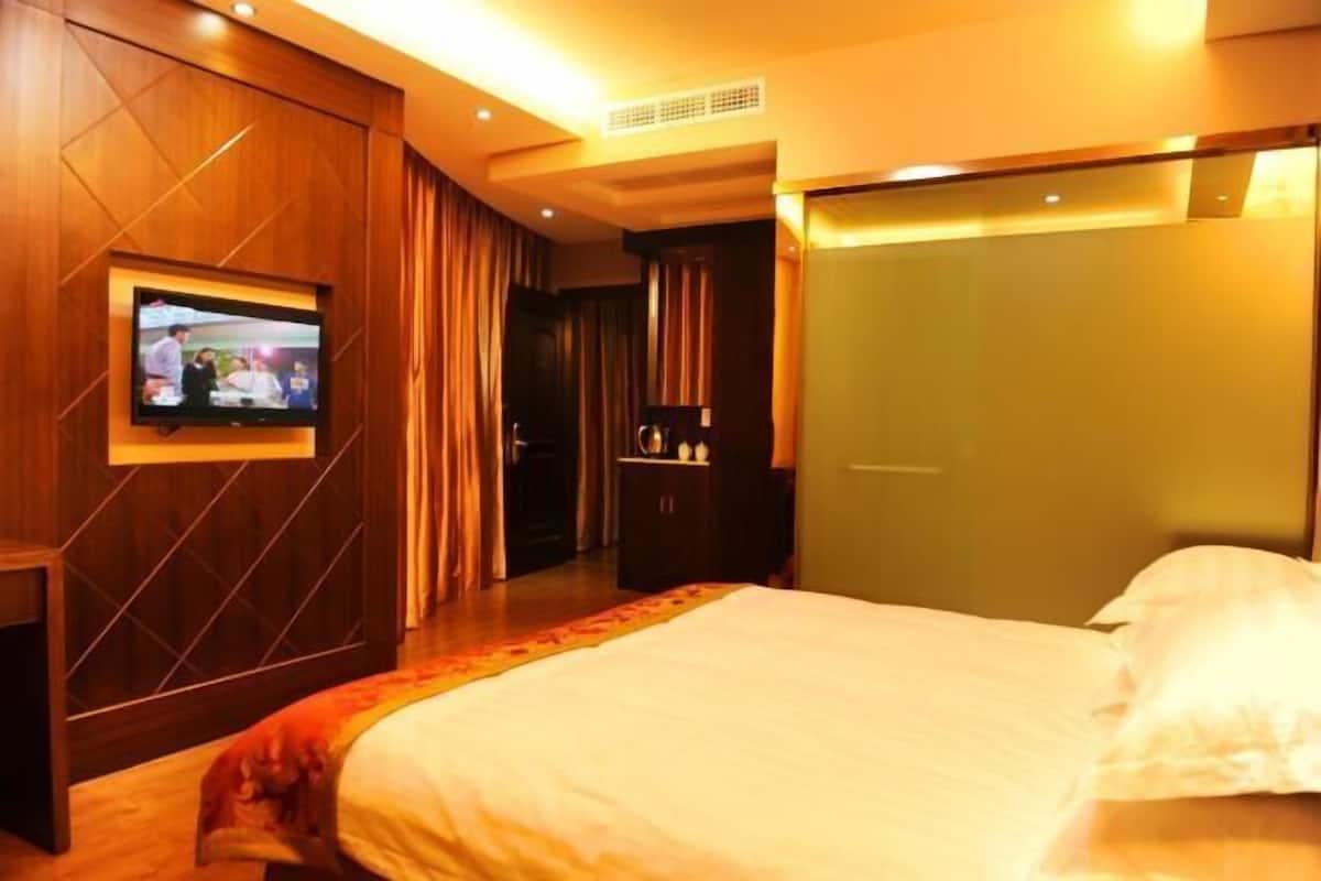 Une chambre d’hôtel avec un grand lit, un téléviseur fixé au mur et une armoire.