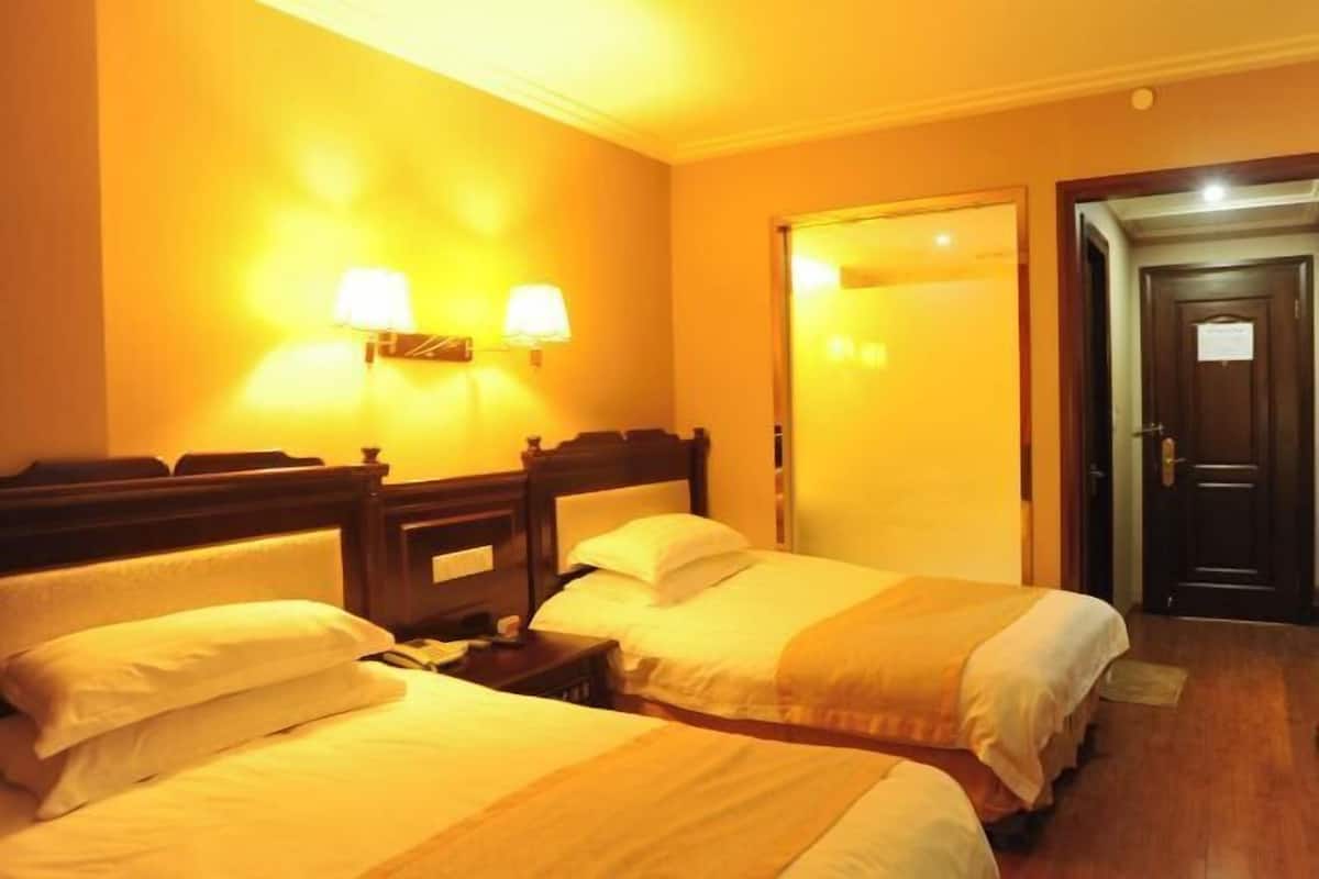 Une chambre d’hôtel avec deux lits, une table de chevet et deux lampes fixées au mur.
