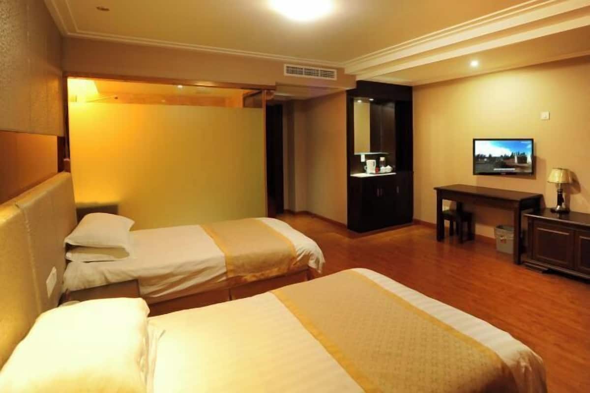 Une chambre d’hôtel avec deux lits, un bureau, une chaise, une télévision et un miroir.