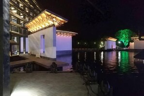 A waterfront hotel with a pool, a covered seating area, and a building with a distinctive roof structure. - Wuzhen Xinyueju(Xizha Scenic Spot, Wuzhen) (Tongxiang)