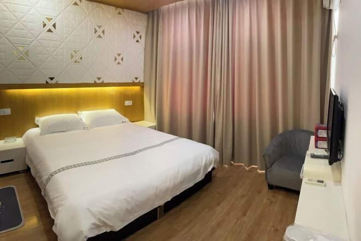 Een hotelkamer met een bed, nachtkastje, stoel en televisie.