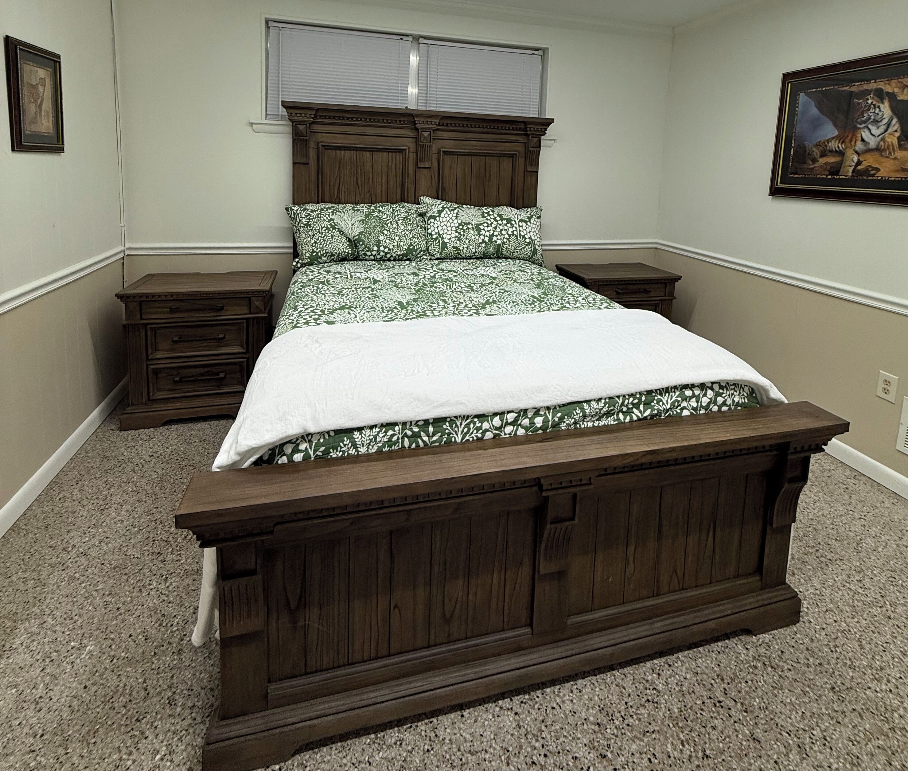 Un dormitorio con una cama de madera, una mesita de noche, un aparador y un cuadro en la pared.