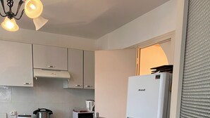 A compact kitchen with white cabinets, a built-in stove, a microwave, and a refrigerator. - Maison Carpe Diem Maximum Pour 4 Personnes (Romilly-sur-Seine)