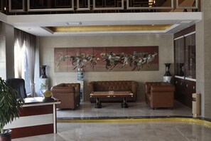 Eine Lobby mit einer Rezeption, zwei Sofas, einem großen abstrakten Gemälde und einer Topfpflanze.