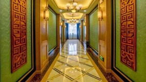 A hallway with a reflective floor, decorative wall panels, and a chandelier. - Wulate Hotel (Urad Front Banner)