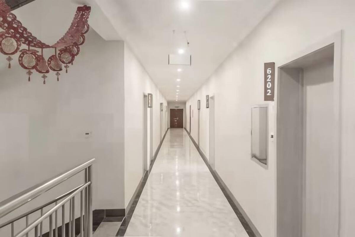 A long, narrow hallway with a polished floor, a metal railing on the left, and a door with the number 6202 on the right.