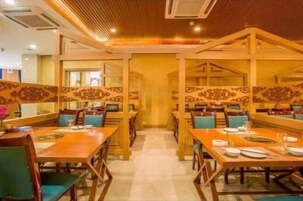 Un restaurante con mesas y sillas de madera, un pasillo central y paneles decorativos en las paredes.