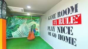 A room with a green carpet, a wall mural with tropical leaves, and a hammock. - Super Apartamento Familiar - Samaria Club Playa (Santa Marta)
