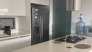 A modern kitchen with a stainless steel refrigerator, a gas stove, and a coffee maker. - Super Apartamento Familiar - Samaria Club Playa (Santa Marta)