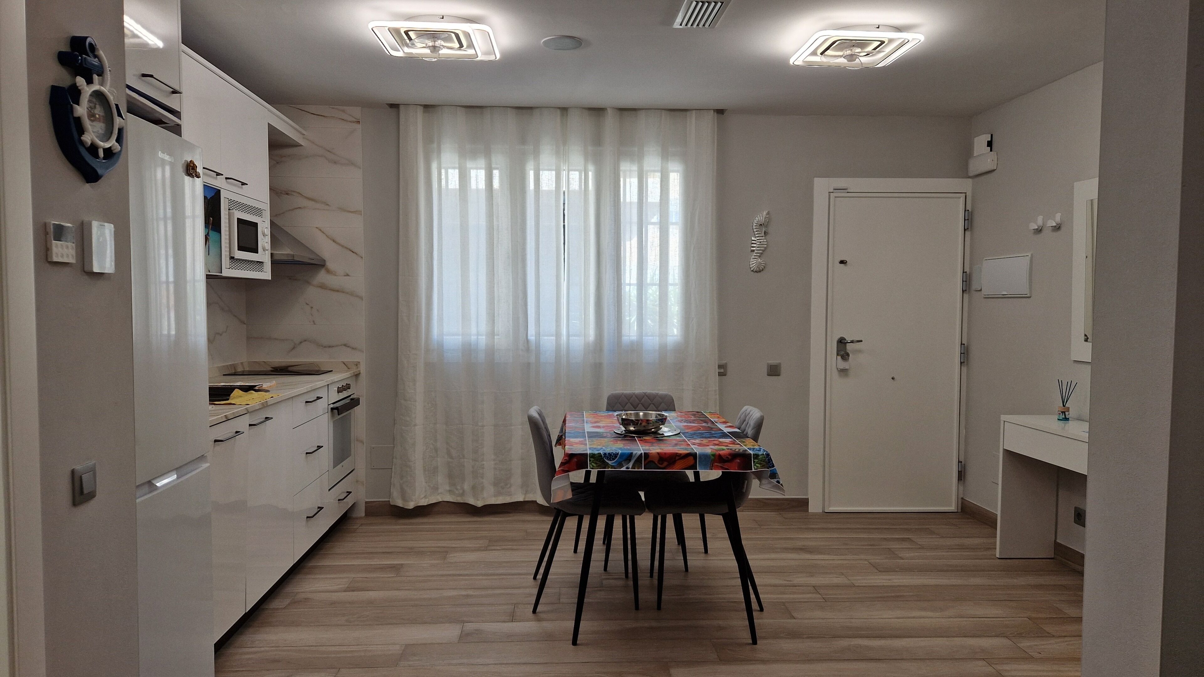Une cuisine de taille réduite comprenant une table à manger, des chaises et un four à micro-ondes.
