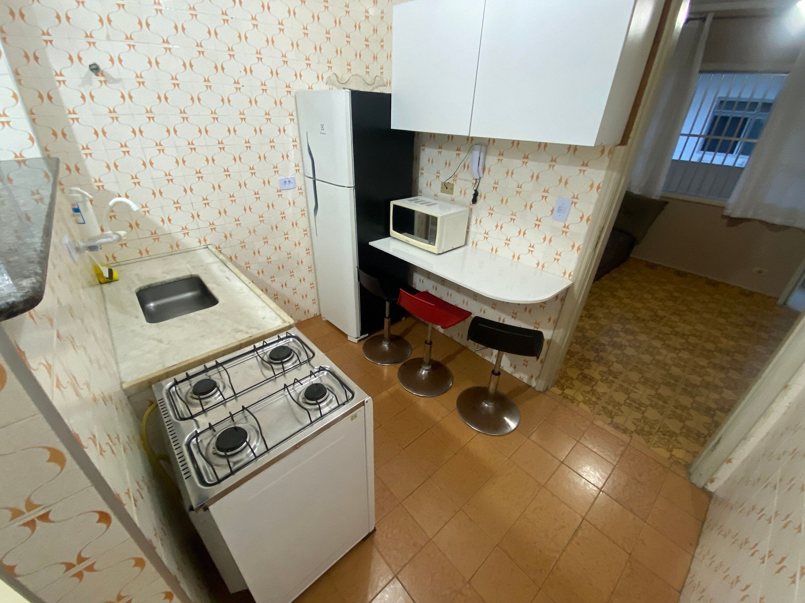 Una cocina compacta con estufa a gas, un fregadero, microondas y una pequeña encimera.