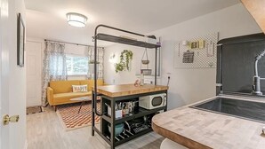 Eine kleine Küche mit einer Holzarbeitsplatte, einer eingebauten Mikrowelle und einem schwarzen Metallregal.