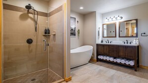 A modern bathroom with a glass-enclosed shower, a freestanding bathtub, and a vanity with a large mirror. - Soak in Panoramic Views • Wapiti Cabin, Dogs OK (Cody)