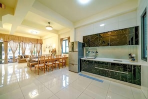 A spacious living area with a dining table and chairs, a kitchen with a marble backsplash, and a large window.