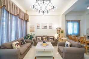 A living room with two sofas, a coffee table, and a dining area with chairs and a table.