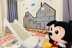A child's play area with a slide, a pegboard wall, and a Mickey Mouse plush toy.