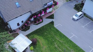 Vue aérienne d’un bâtiment avec un parking, un espace extérieur abrité avec des sièges et un petit jardin.
