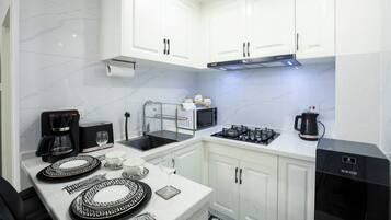 Una cocina moderna con armarios blancos, una campana extractora de acero inoxidable y una cafetera.