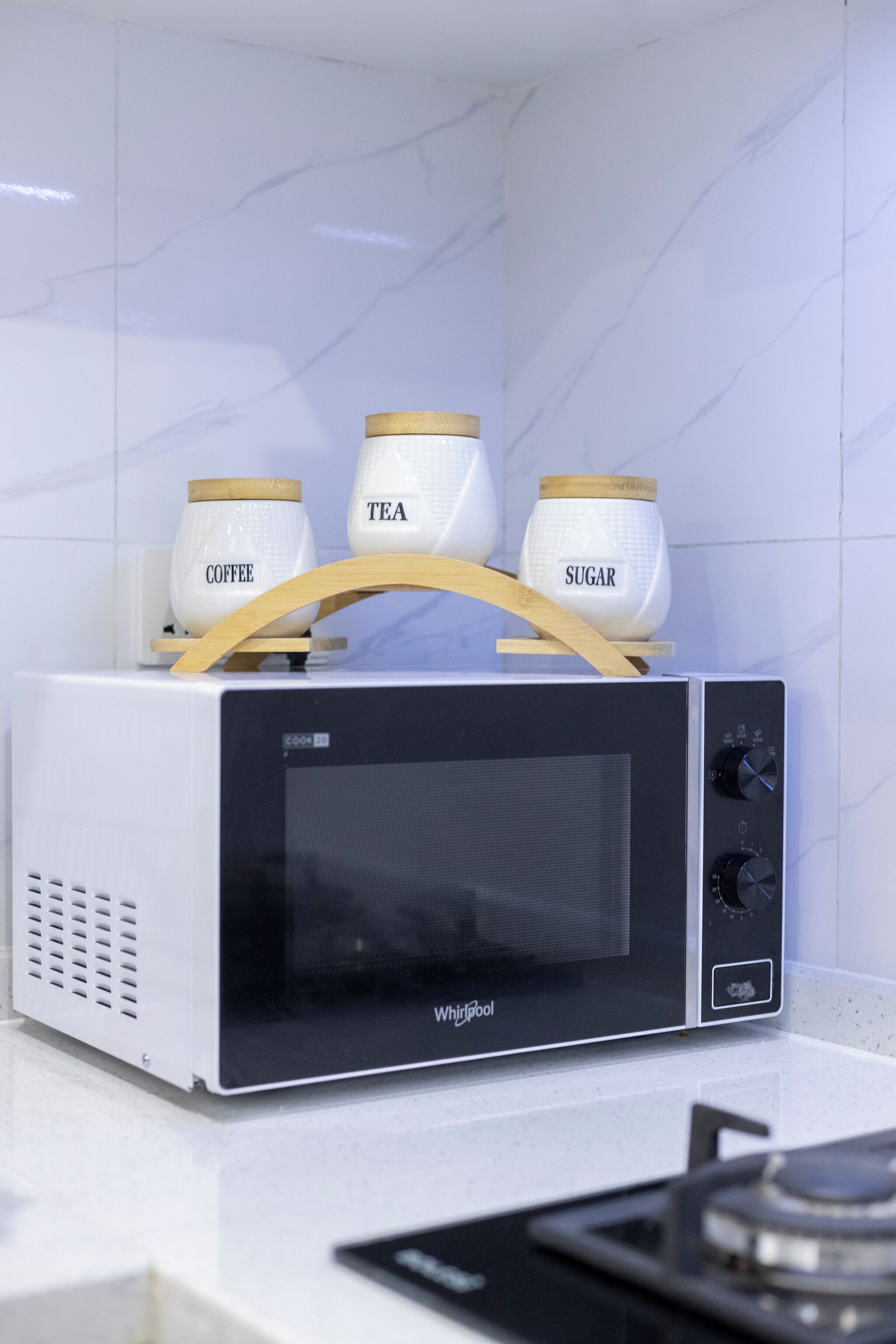 Un four à micro-ondes Whirlpool doté d’une poignée en bois, posé sur un plan de travail blanc.