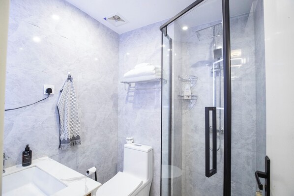 A modern bathroom with a glass-enclosed shower, a white sink, and a towel rack. - Alba Garden (Nairobi)