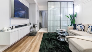 A modern living room with a flat-screen TV, a sofa, a coffee table, and a large plant. - Alba Garden (Nairobi)