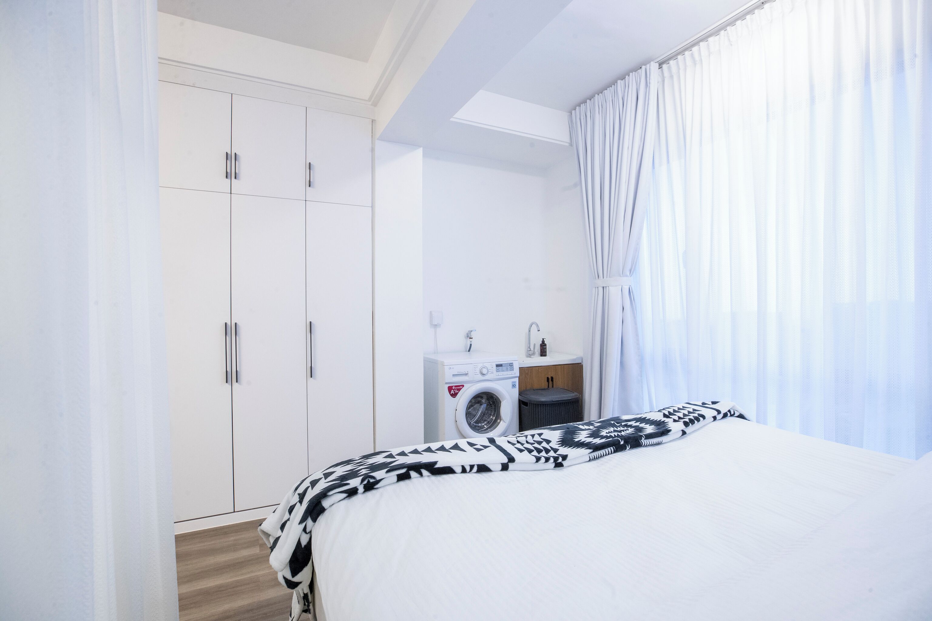 Ein Schlafzimmer mit Bett, Waschmaschine, Spüle und Kleiderschrank.