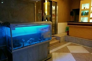 Un hall de hotel con un gran acuario, una recepción y un mostrador de registro.