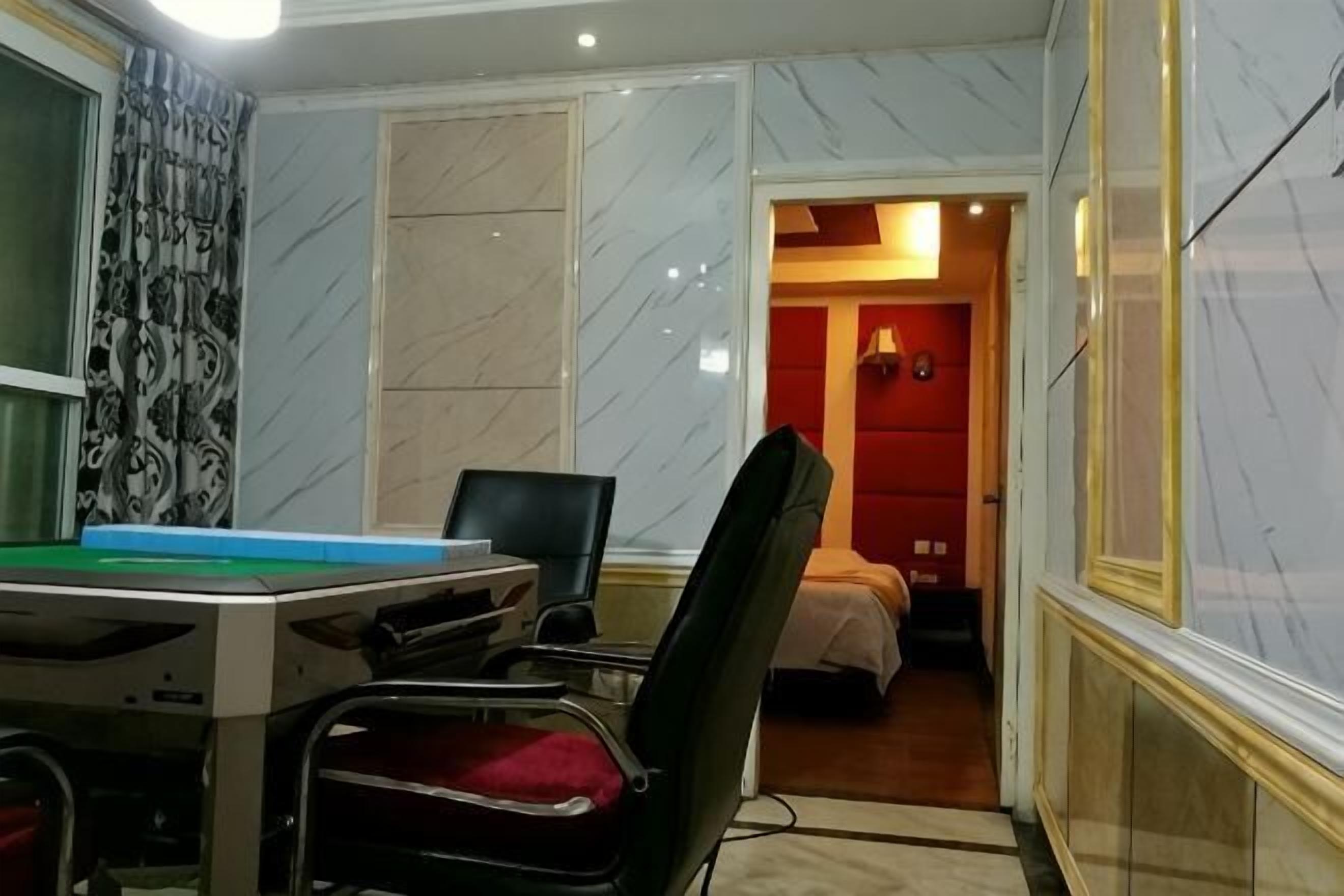 Een kamer met een tafelvoetbaltafel, een stoel, een bed en een rode muur.