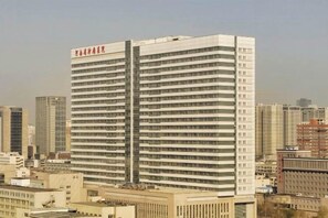 Un hotel moderno de gran altura con un llamativo letrero vertical y múltiples pisos.