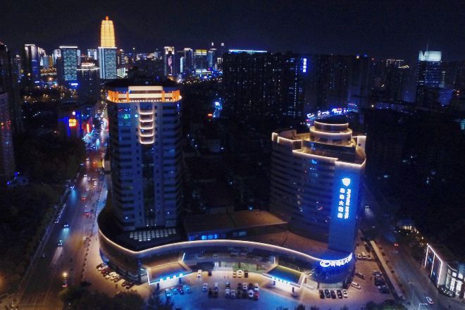 A high-rise building with a curved entrance and illuminated signage.