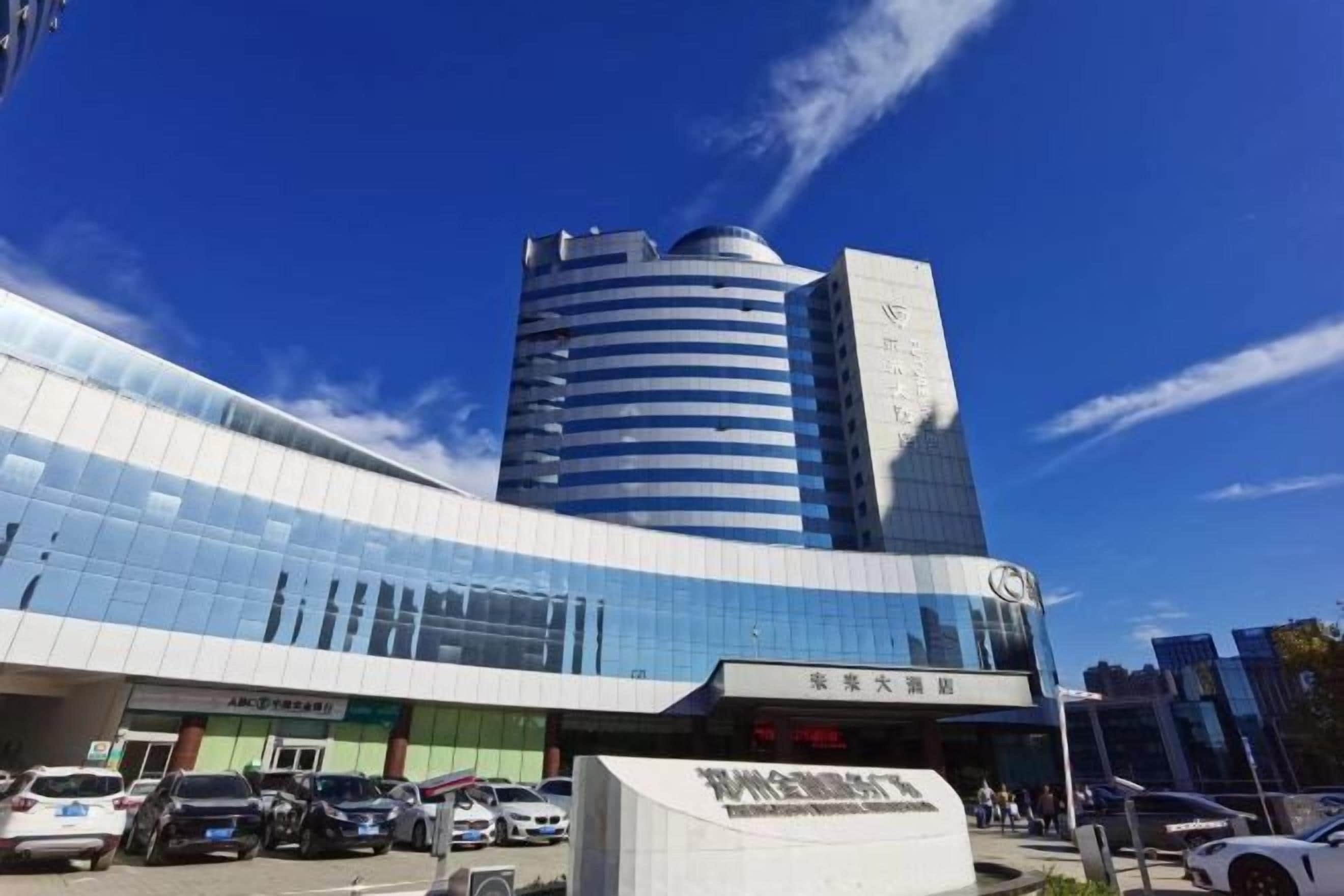 Un edificio moderno con fachada de vidrio curvada, una destacada torre cilíndrica y un cartel que indica un centro de negocios.