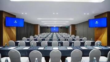 Un salón de conferencias con filas de mesas y sillas, equipado con botellas de agua y tarjetas de identificación.