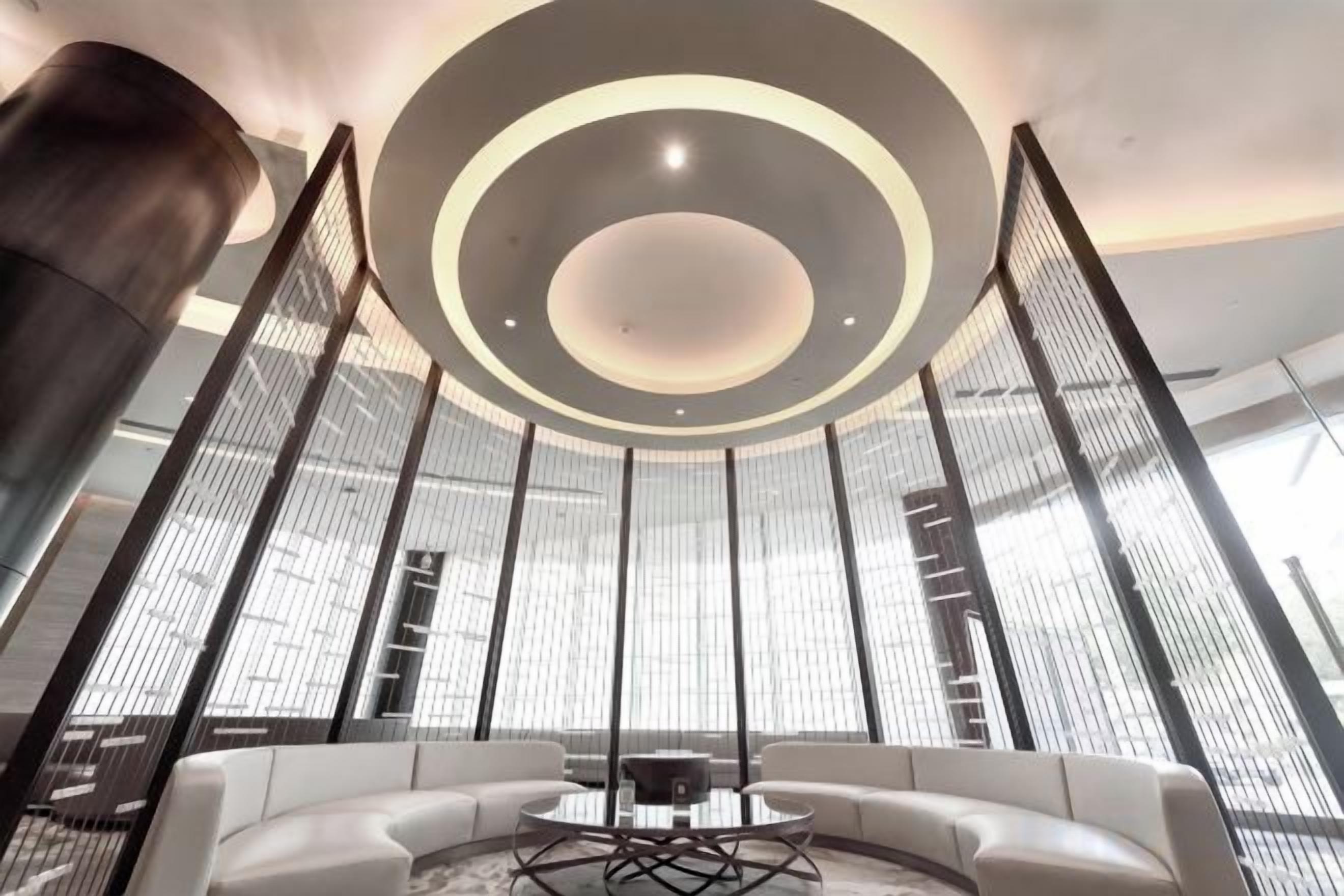 A modern interior with a circular ceiling design, a seating area with a round table, and tall vertical elements.