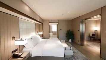 A modern hotel room with a large bed, bedside tables, a mirror, and a view into the bathroom.