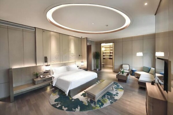A modern hotel room with a large bed, a seating area, a TV, and a circular ceiling light. - Future Hotel (Zhengzhou)