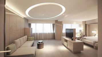 A modern hotel room with a sofa, TV, and a bed.