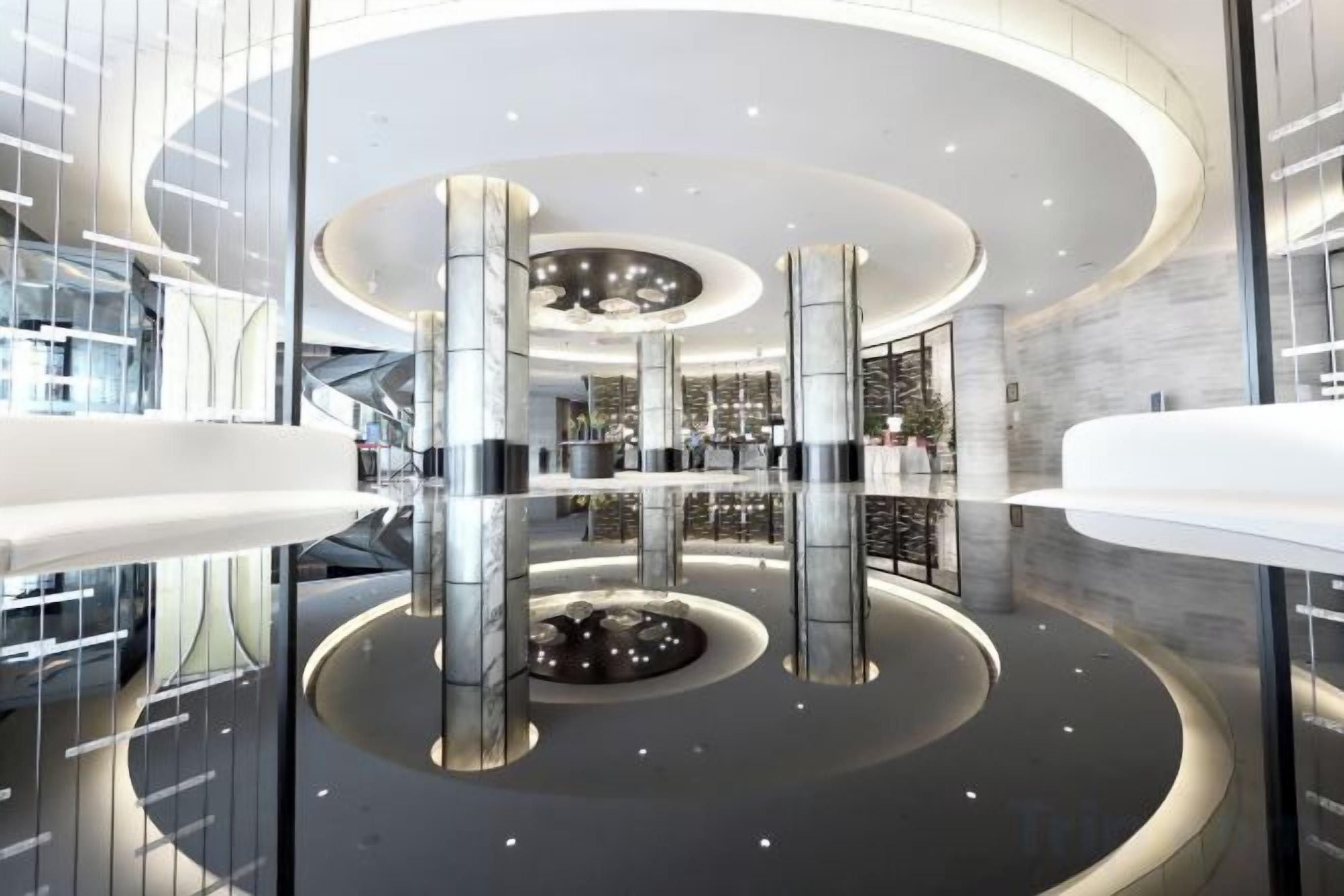 A modern lobby with a circular design, glass railings, and a central reflective feature.