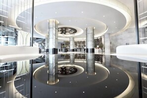 A modern lobby with a circular design, glass railings, and a central reflective feature. - Future Hotel (Zhengzhou)