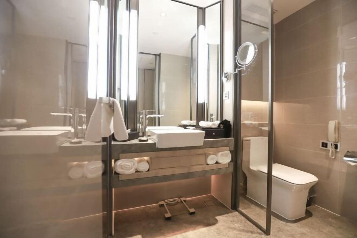 A modern bathroom with a glass shower enclosure, a sink, a toilet, and a mirror.
